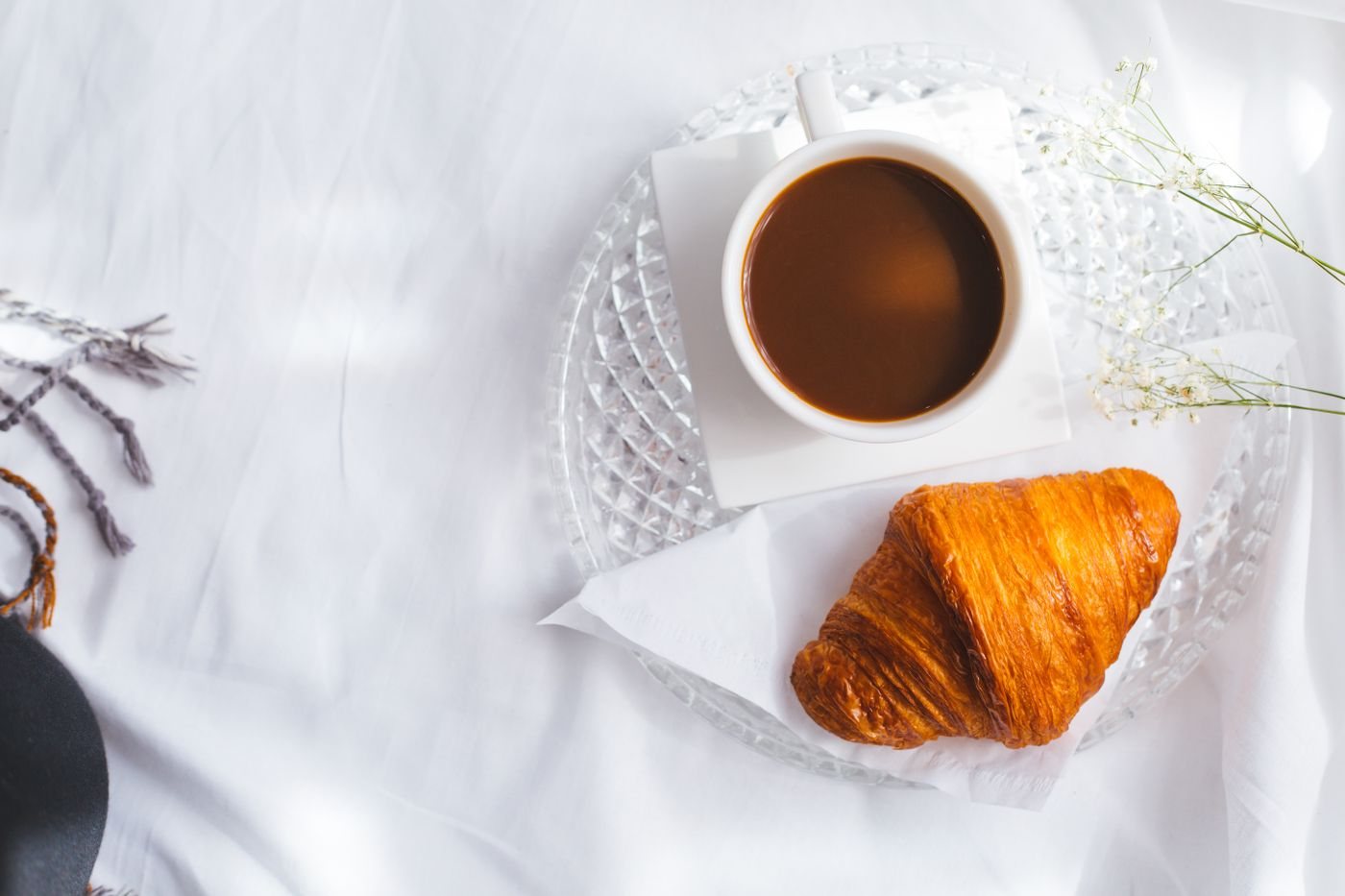 A croissant beside a cup of coffee at breakfast