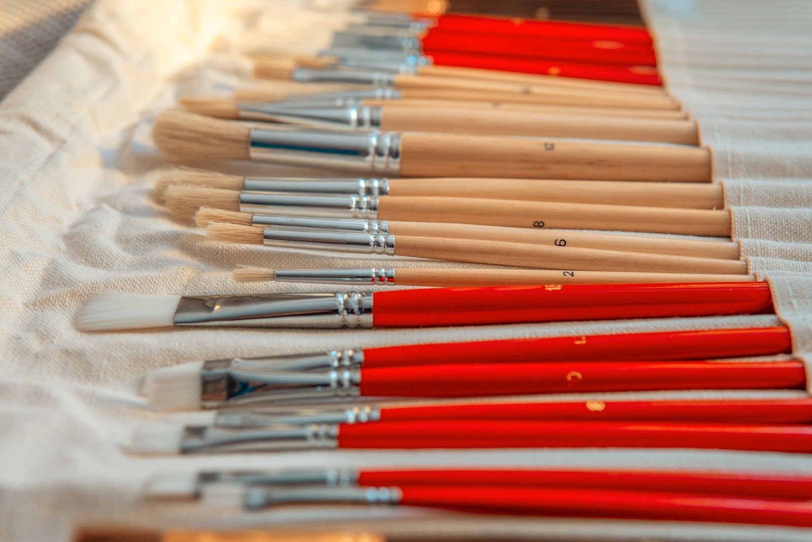 An assortment of art brushes laid on canvas fabric