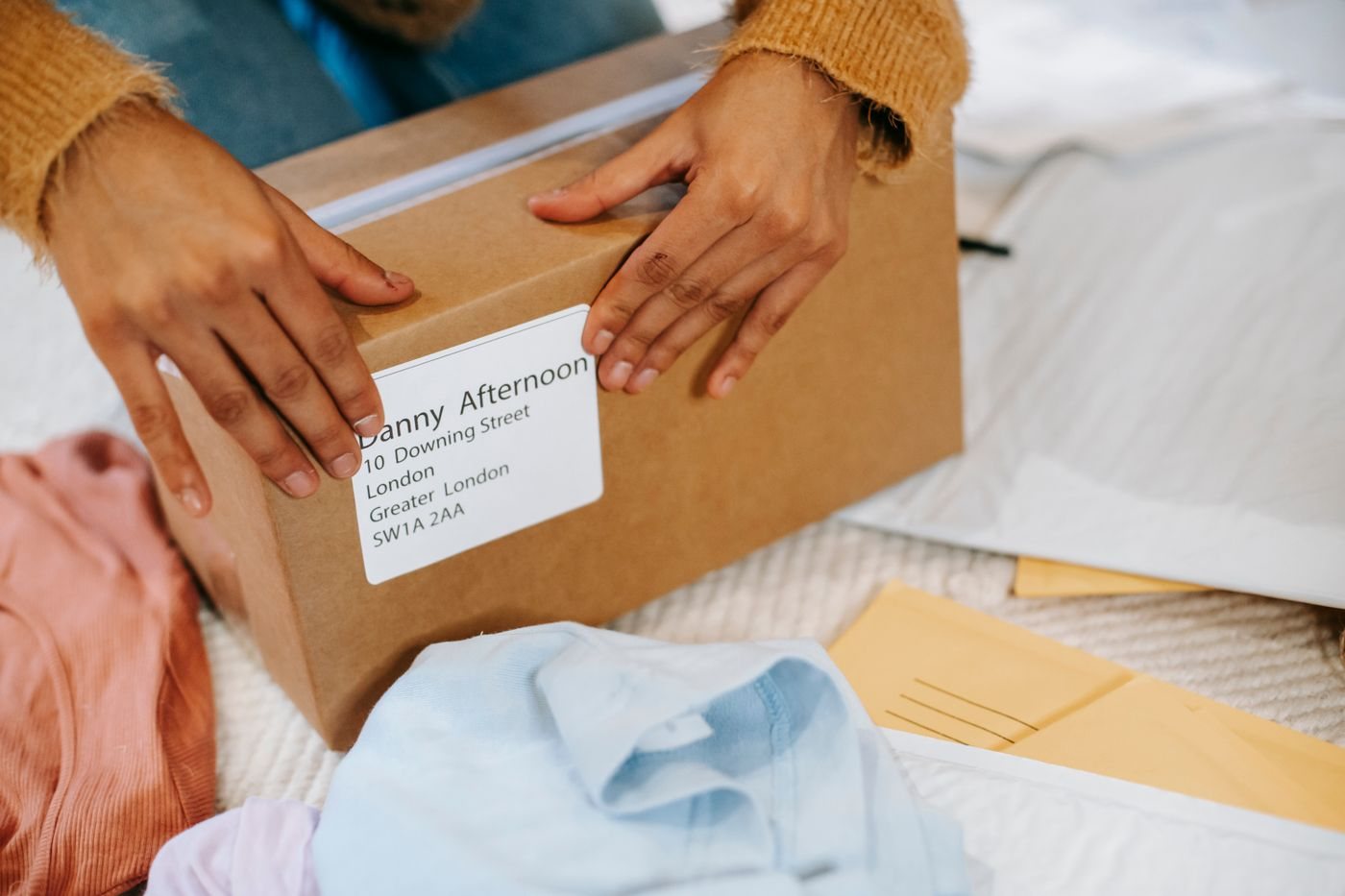 A person packing a cardboard parcel at a table