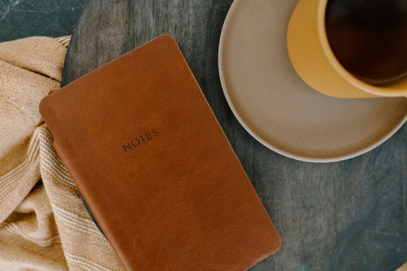 Leather notebook beside a coffee cup on a wooden table