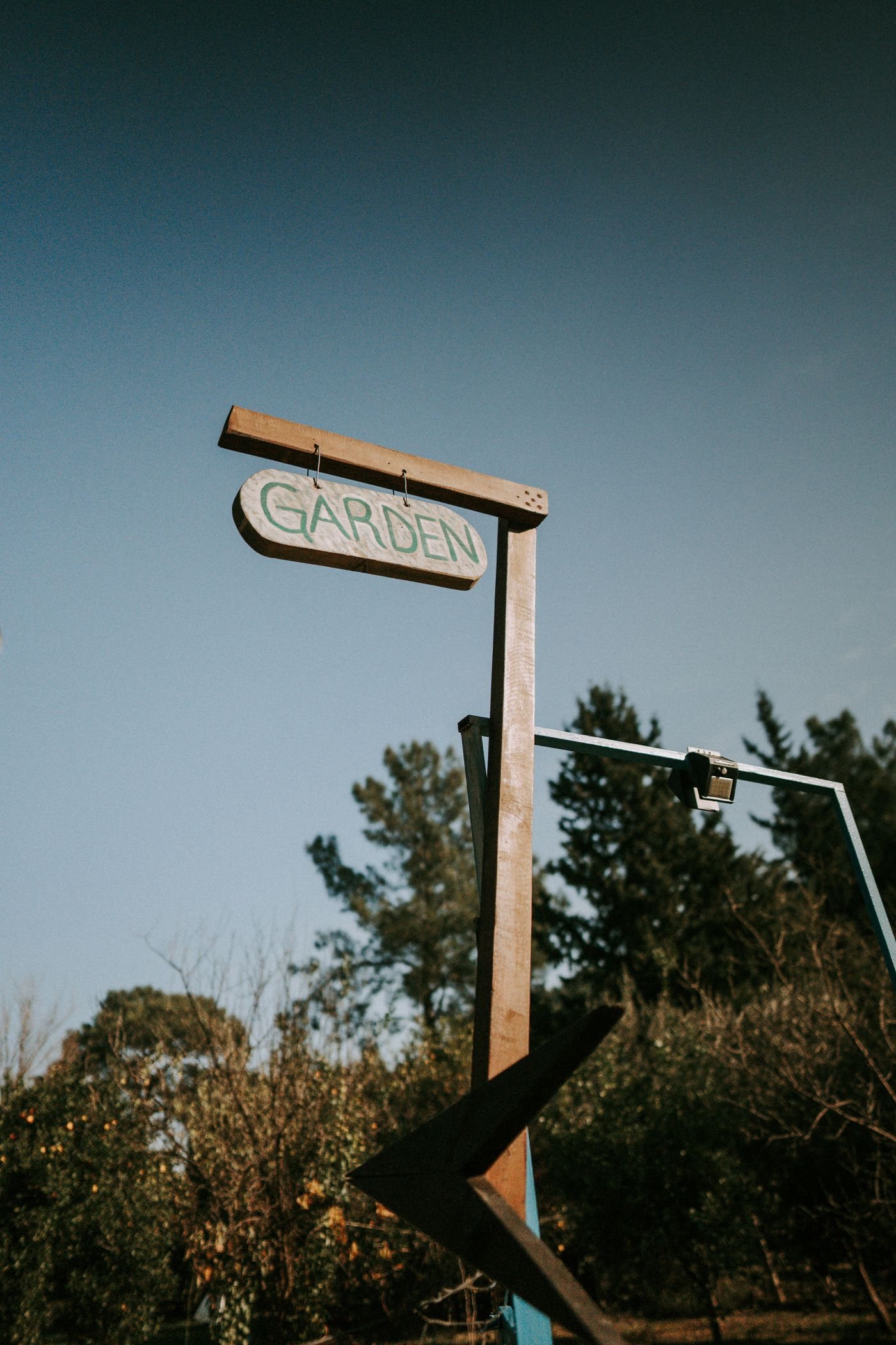 A garden sign hanging against a blue sky