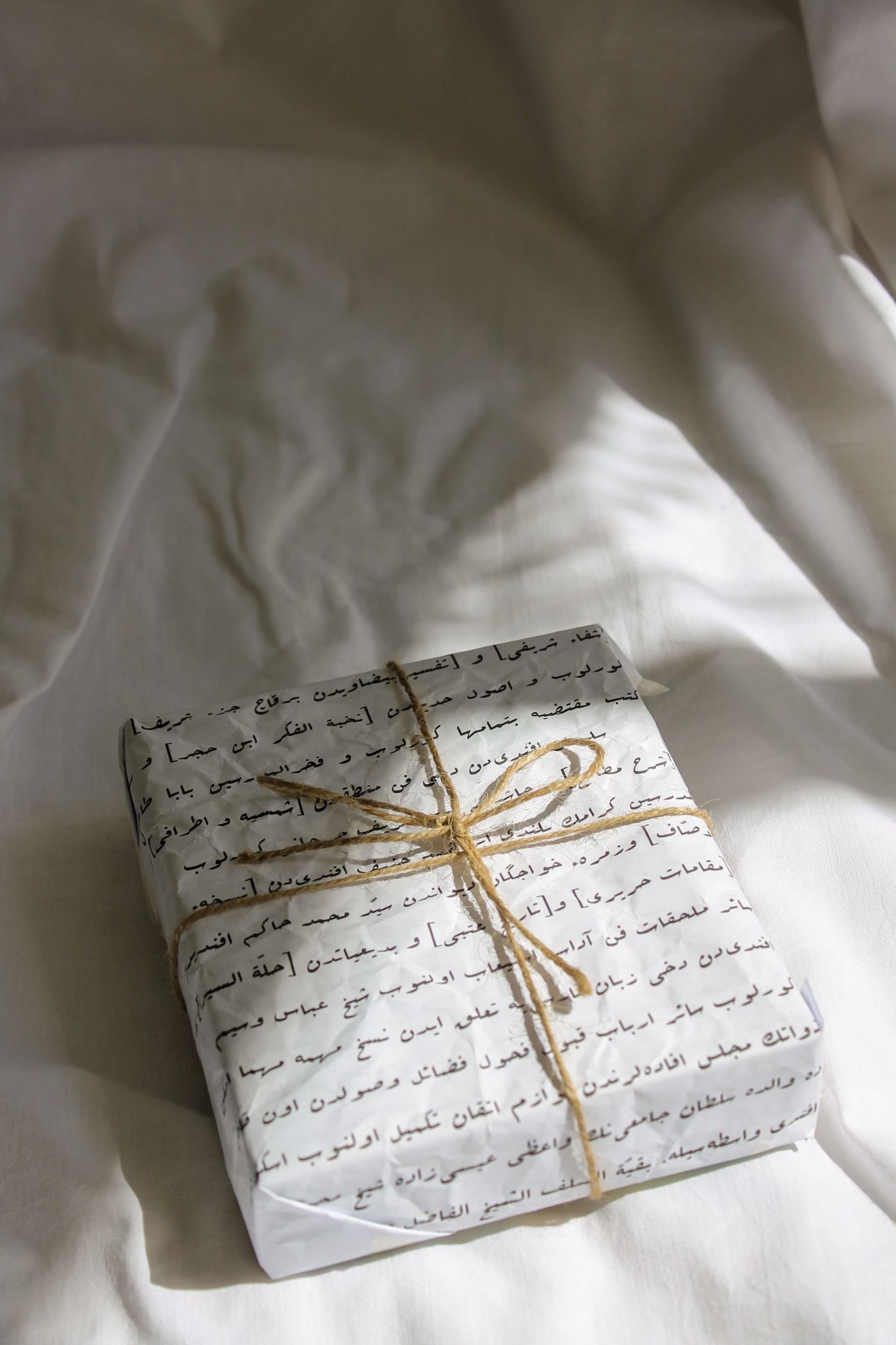 A small gift wrapped in printed paper and twine