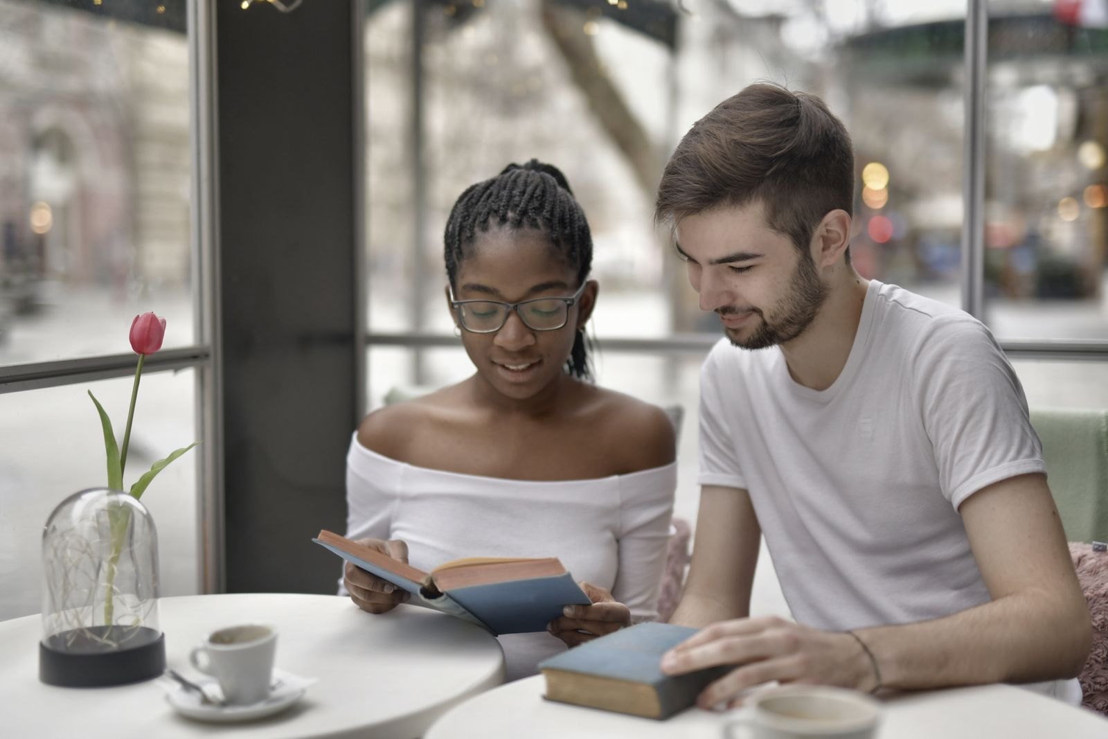 Two people reading books together at a cafe table