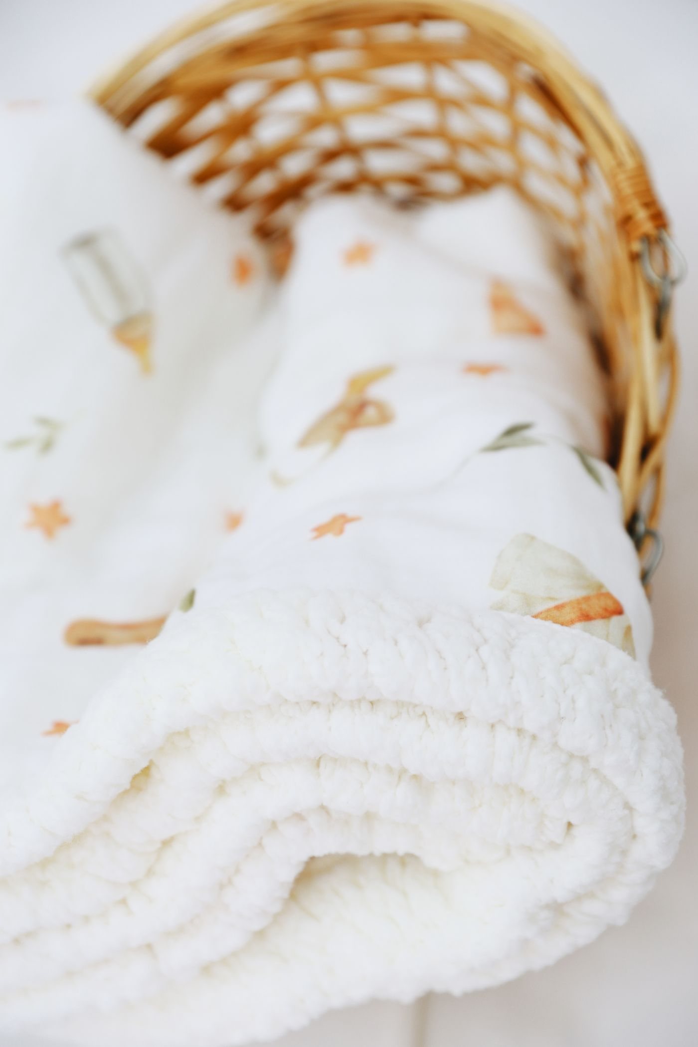 White baby blanket with playful designs in a wicker basket