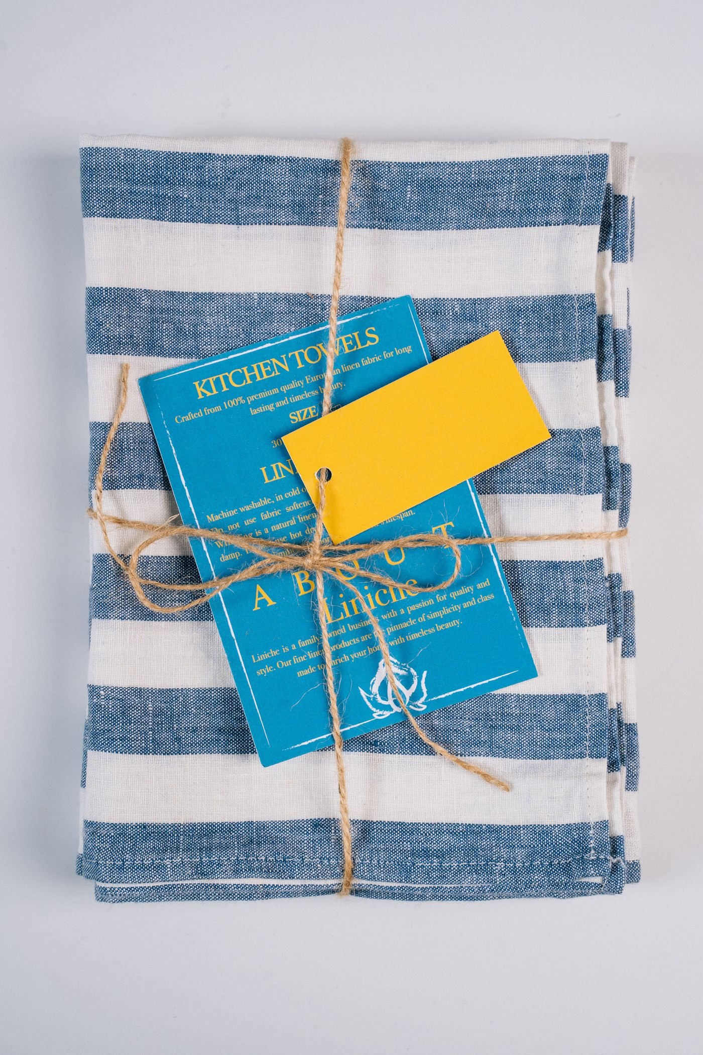 Folded blue and white kitchen textiles with a paper band
