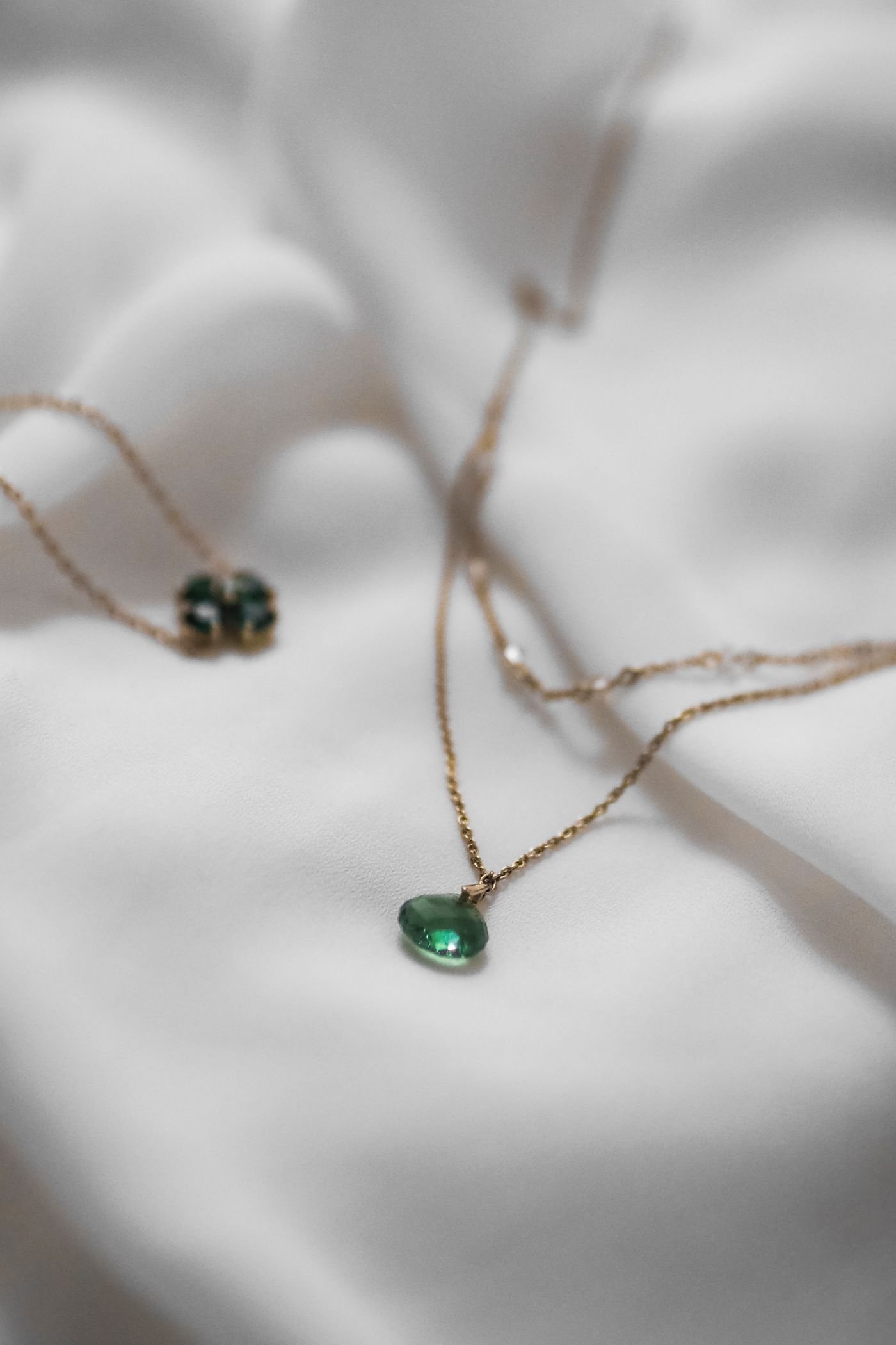 Green gemstone pendant on soft white fabric