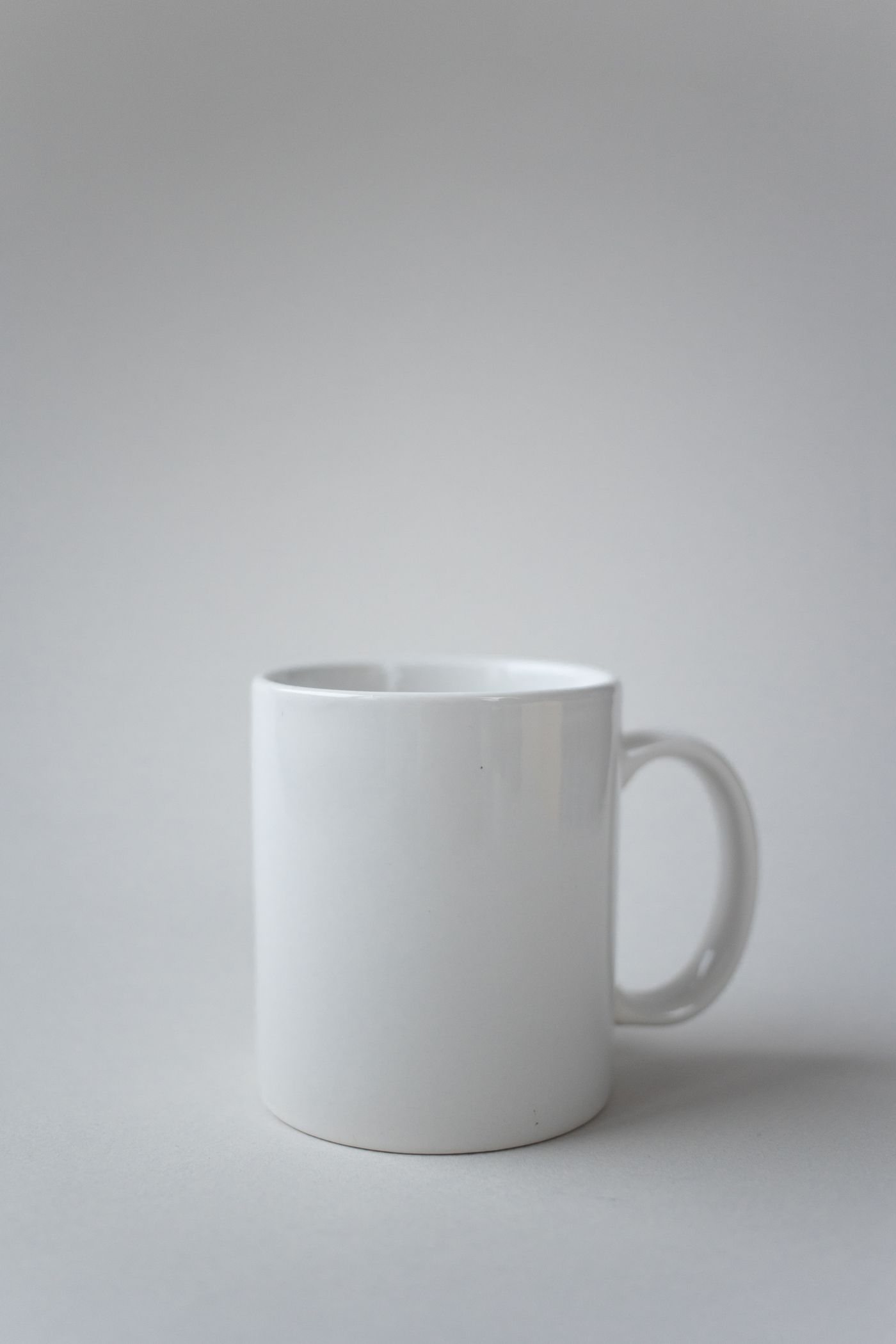 A plain white ceramic mug on a light surface