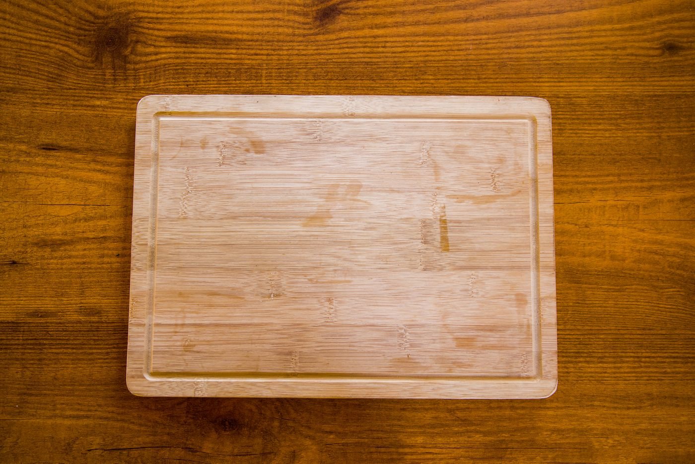 A bamboo chopping board on a textured wooden surface