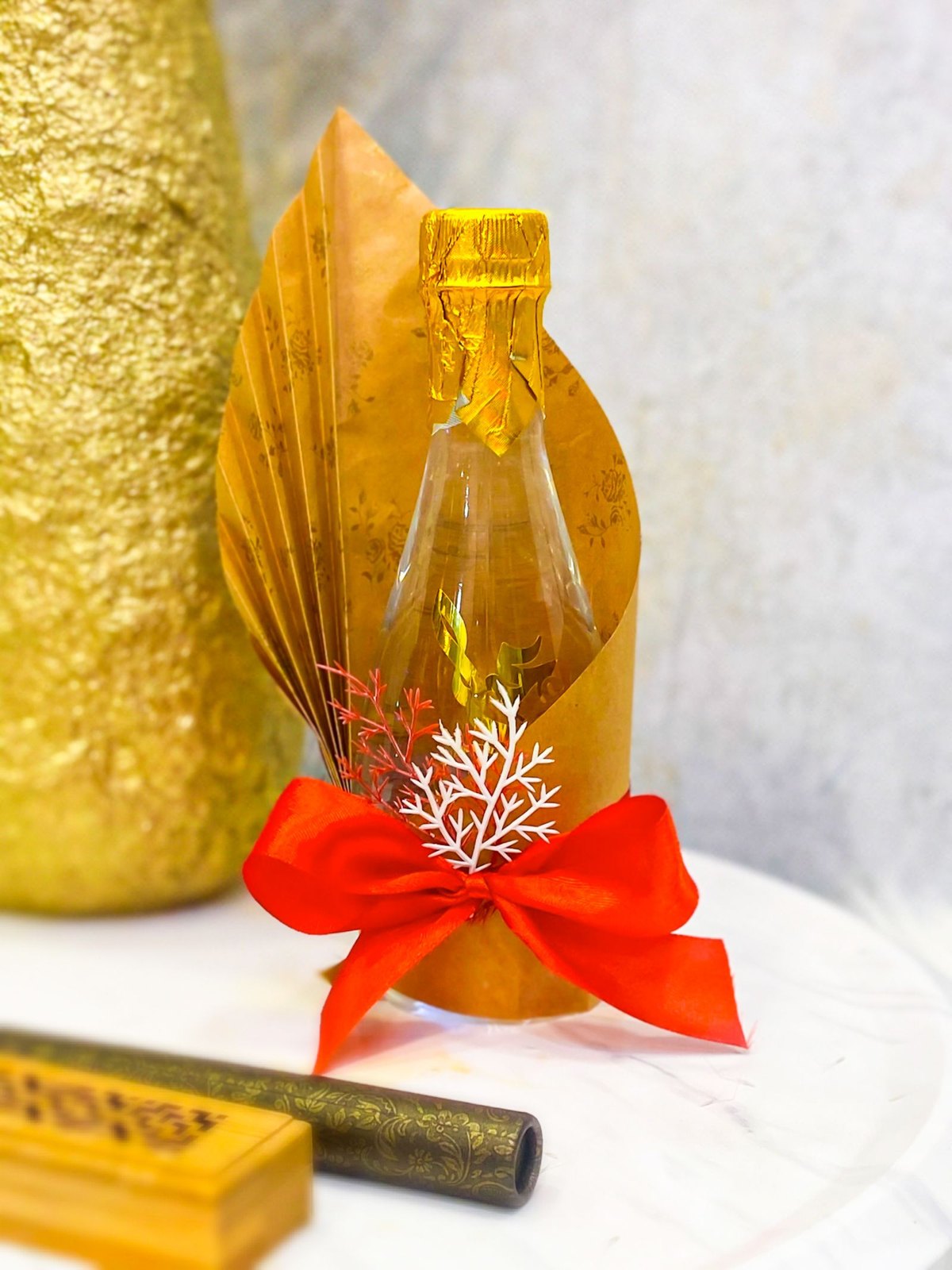 Bottle-shaped gift wrapped in gold paper with a red ribbon